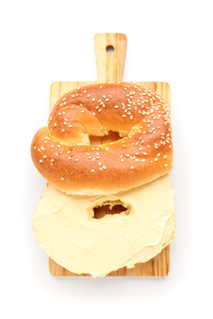 Wooden board of tasty bagel with cream cheese on white backgroundの写真素材