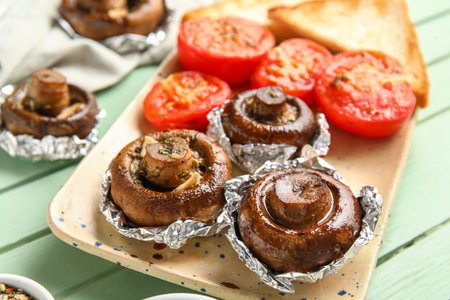 Plate with tasty baked mushrooms and tomatoes on color wooden background, closeupの写真素材