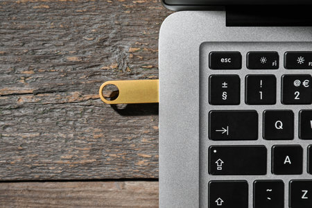 Modern laptop with USB flash drive on wooden background, closeupの写真素材