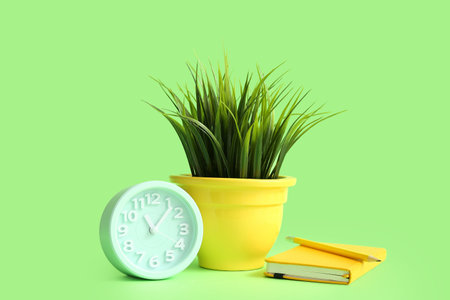 Artificial grass with notebook and alarm clock on green backgroundの写真素材