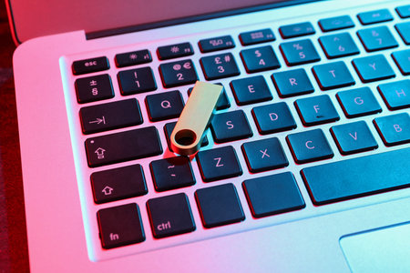 Metallic USB flash drive on modern laptop, closeup