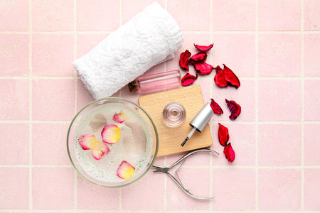 Composition with bottles of cuticle oil, towel, nail cutter and flower petals on color tile backgroundの写真素材