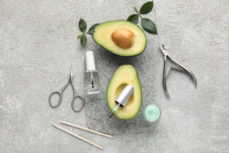 Composition with bottles of cuticle oil, manicure instruments and avocado on grunge backgroundの写真素材