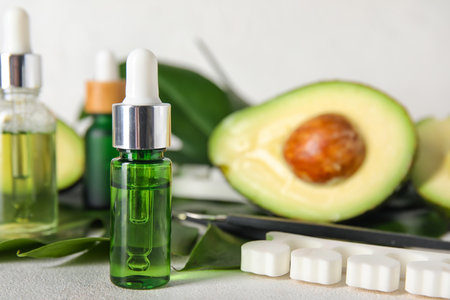 Bottles of cuticle oil, manicure instruments and avocado on light background, closeupの写真素材