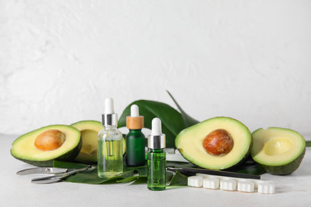 Composition with bottles of cuticle oil, manicure instruments, avocado and palm leaf on light backgroundの写真素材