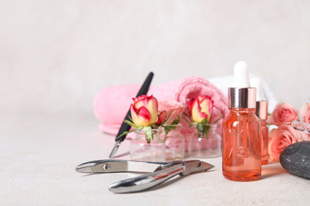 Composition with bottles of cuticle oil, manicure instruments, towels and rose flowers on light backgroundの写真素材
