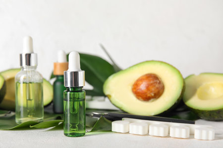 Composition with bottles of cuticle oil, manicure instruments, avocado and palm leaf on light background, closeupの写真素材