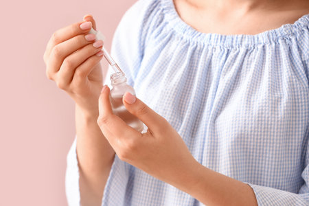 Woman with bottle of cuticle oil near color wallの写真素材