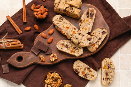 Composition with tasty biscotti cookies, nuts, cinnamon and chocolate on light tile backgroundの写真素材