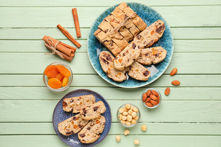 Composition with tasty biscotti cookies, nuts, cinnamon and dried apricots on color wooden backgroundの写真素材