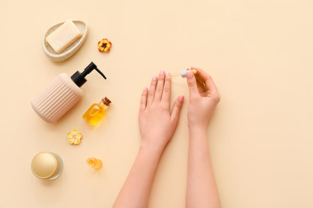 Female hands with cuticle oil and cosmetic products on color backgroundの写真素材