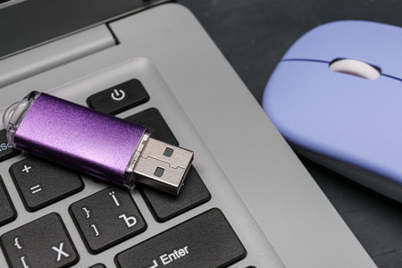 Modern laptop, purple USB flash drive and blue mouse on black grunge backgroundの写真素材