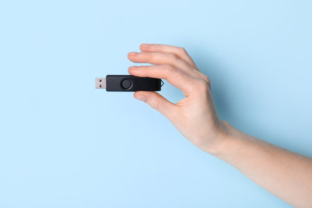 Woman holding black USB flash drive on blue backgroundの写真素材