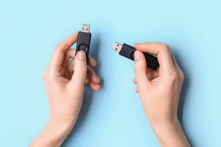 Woman holding black USB flash drives on blue backgroundの写真素材