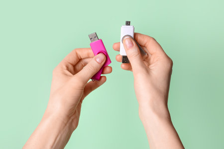 Woman holding pink and white USB flash drives on green backgroundの写真素材
