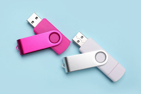 Pink and white USB flash drives on blue background
