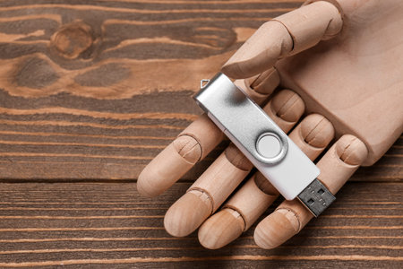 Mannequin hand with USB flash drive on wooden background, closeup