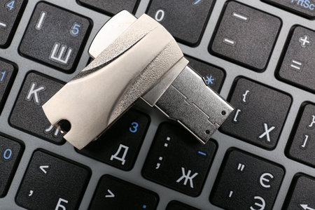 Metallic USB flash drive on modern laptop, closeup