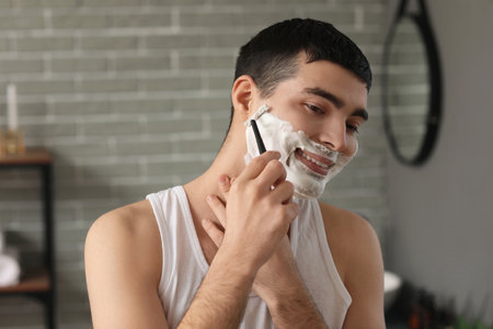 Young man shaving in the bathroomの写真素材