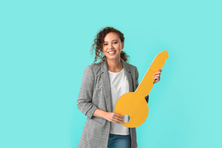 Happy young woman with big paper key on color backgroundの写真素材