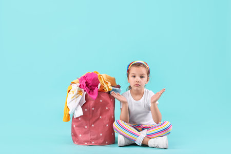 Little girl with dirty laundry on color backgroundの写真素材