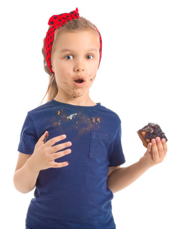 Little girl in dirty clothes eating chocolate on white backgroundの写真素材