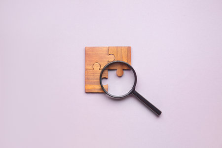 Pieces of jigsaw puzzle and magnifier on light background. unity conceptの写真素材