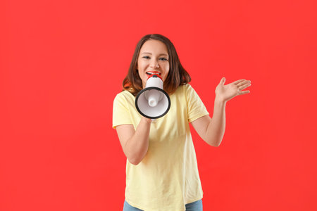 Beautiful young woman with megaphone on color backgroundの写真素材