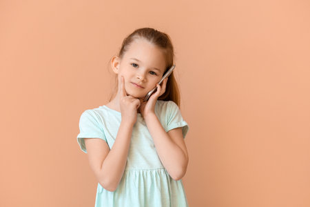 Cute little girl talking by phone on color backgroundの写真素材