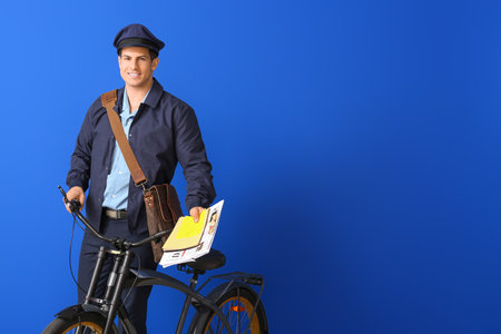 Handsome young postman with bicycle on color backgroundの写真素材