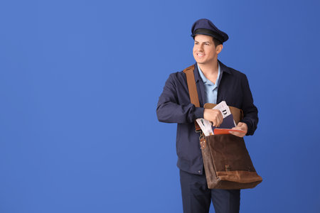 Handsome young postman on color backgroundの写真素材