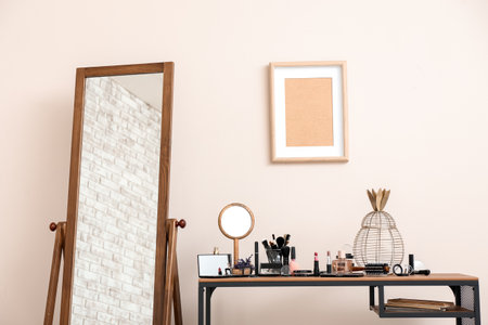 Table with set of decorative cosmetics and mirror in the roomの写真素材