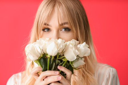 Beautiful young woman with bouquet of roses on color backgroundの写真素材