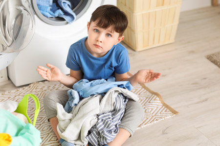 Sad little boy with dirty clothes at homeの写真素材
