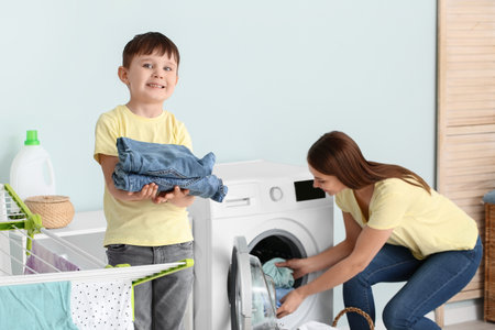 Young woman with her little son doing laundry at homeの写真素材