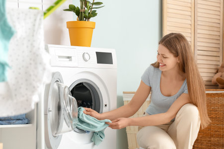 young woman doing laundry at homeの写真素材