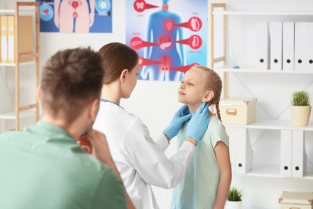 Doctor examining little girl with thyroid gland problem in clinicの写真素材