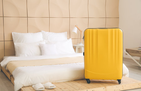 Suitcase near bed in hotel roomの写真素材