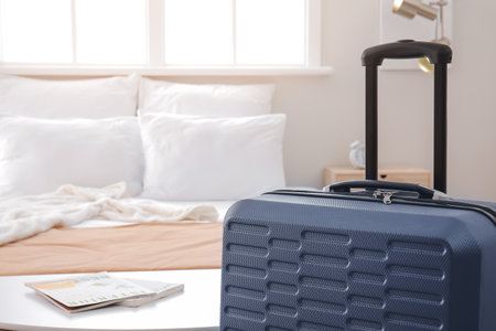 Suitcase near bed in hotel roomの写真素材