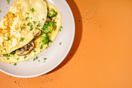 Tasty omelet with broccoli and mushrooms on orange backgroundの写真素材