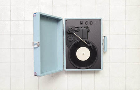 Record player with vinyl disk on white tile background