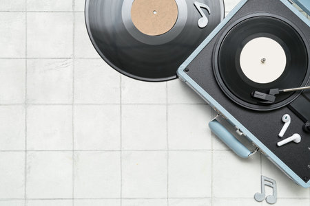 Record player with vinyl disks, earphones and note signs on white tile background
