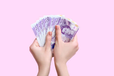 Woman with hryvnia banknotes on pink background