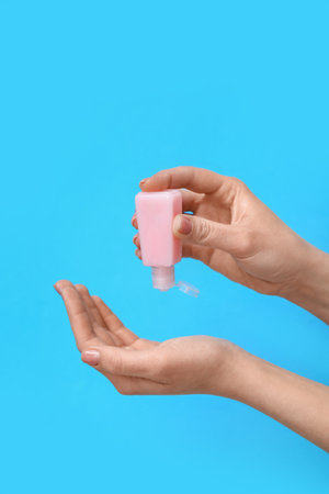 Woman applying sanitizer on blue backgroundの写真素材