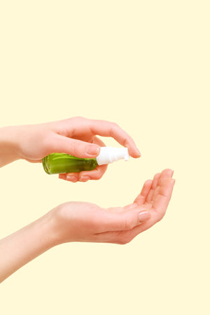 Woman applying sanitizer on beige backgroundの写真素材