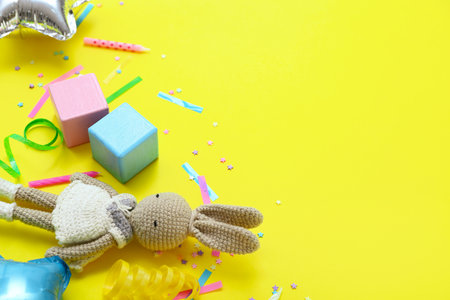 Baby toys with confetti on yellow background, closeup. Children's Day celebrationの写真素材