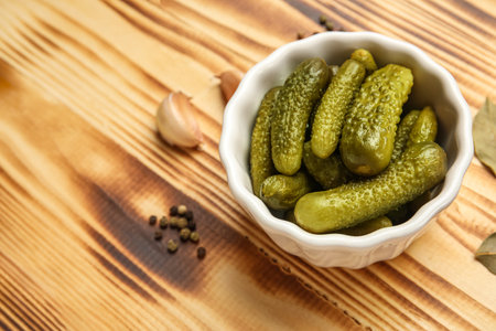 Bowl with tasty fermented cucumbers and ingredients on wooden backgroundの写真素材
