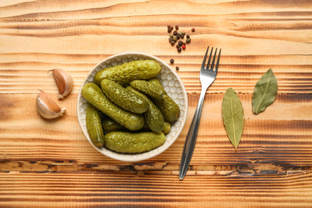Bowl with tasty fermented cucumbers and ingredients on wooden backgroundの写真素材