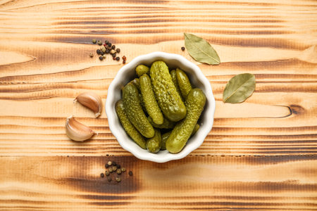 Bowl with tasty fermented cucumbers and ingredients on wooden backgroundの写真素材