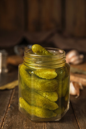 Jar with tasty fermented cucumbers on wooden tableの写真素材